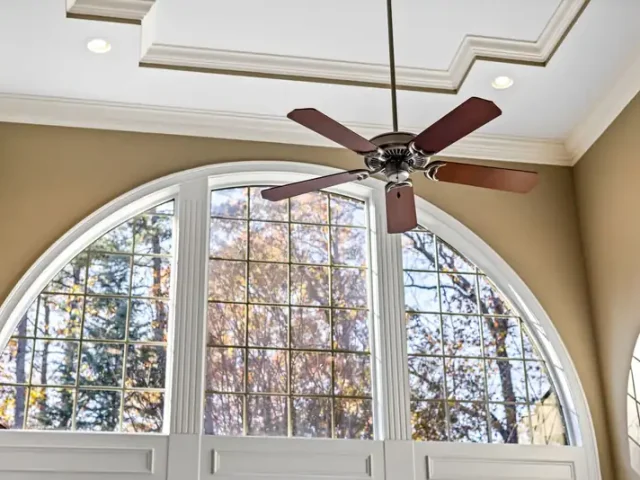 Ceiling fan in a bright room with a tall arched window
