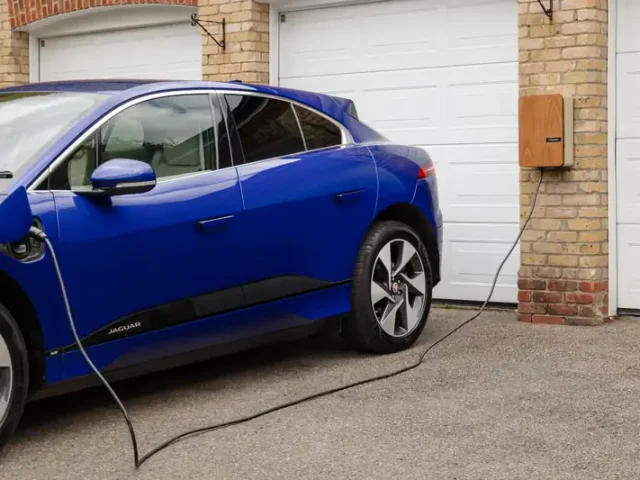 Electric car charging from a wall charger outside a home garage