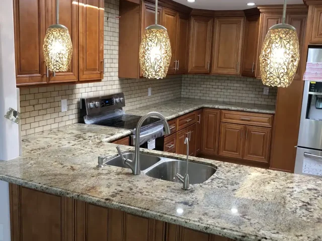 Kitchen with three glass pendant lights over the island and recessed ceiling lights