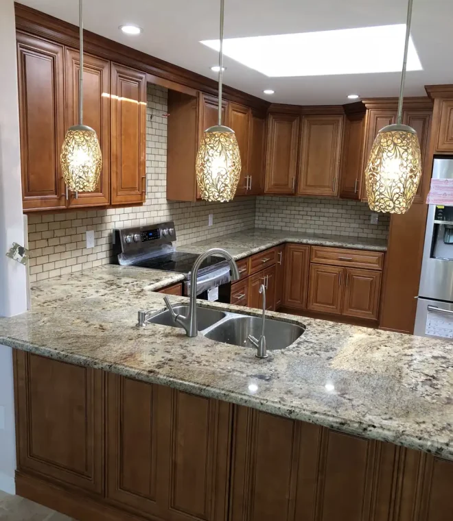 Kitchen with three glass pendant lights over the island and recessed ceiling lights